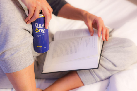 Someone drinking a Day One and reading a book